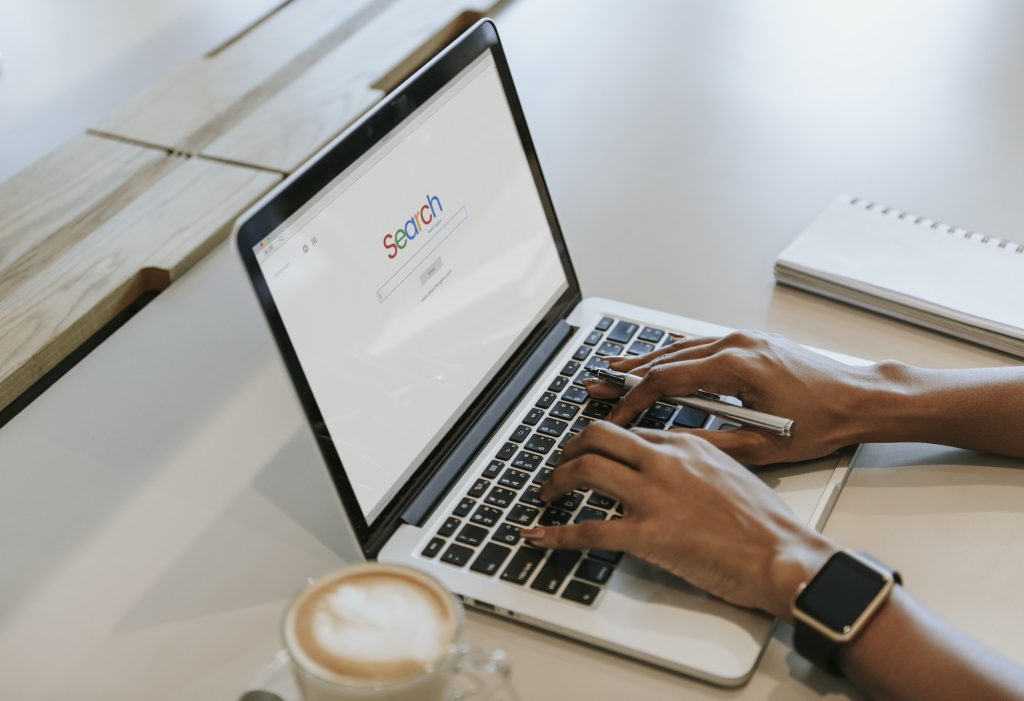 Laptop sobre un escritorio, y una persona buscando en Google